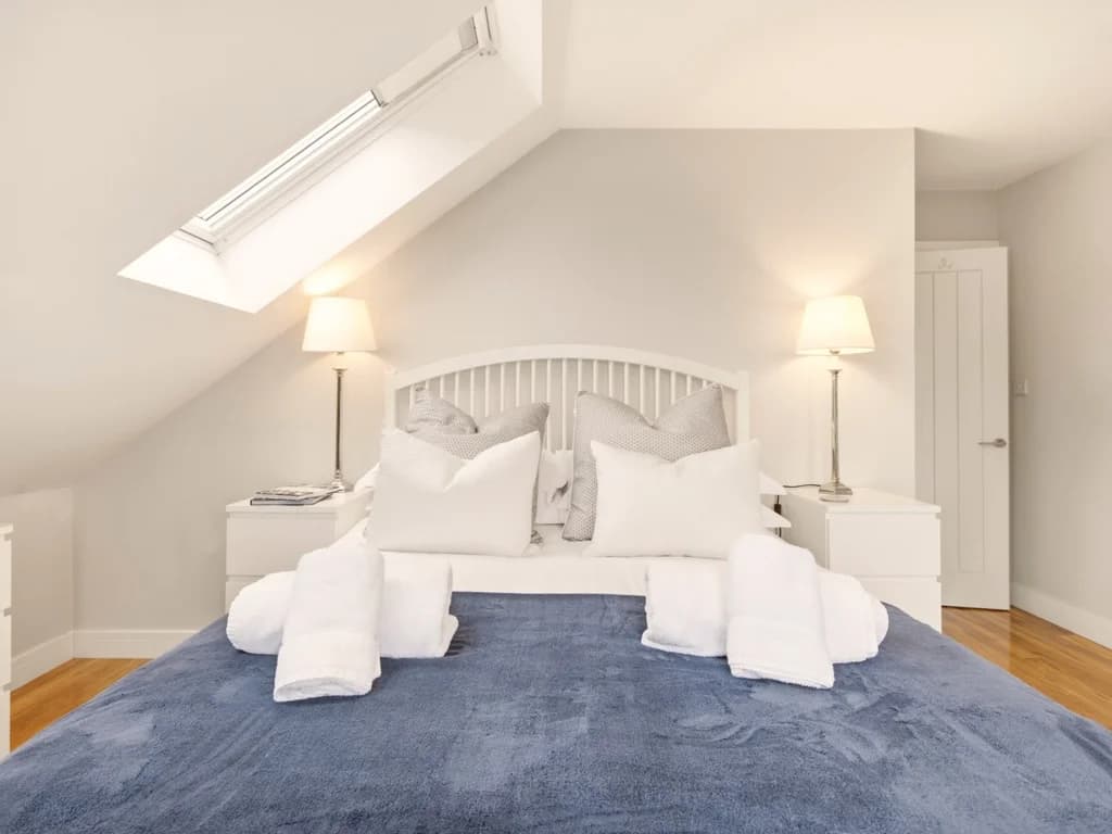 First-floor king bedroom with white spindle bed and vaulted ceiling