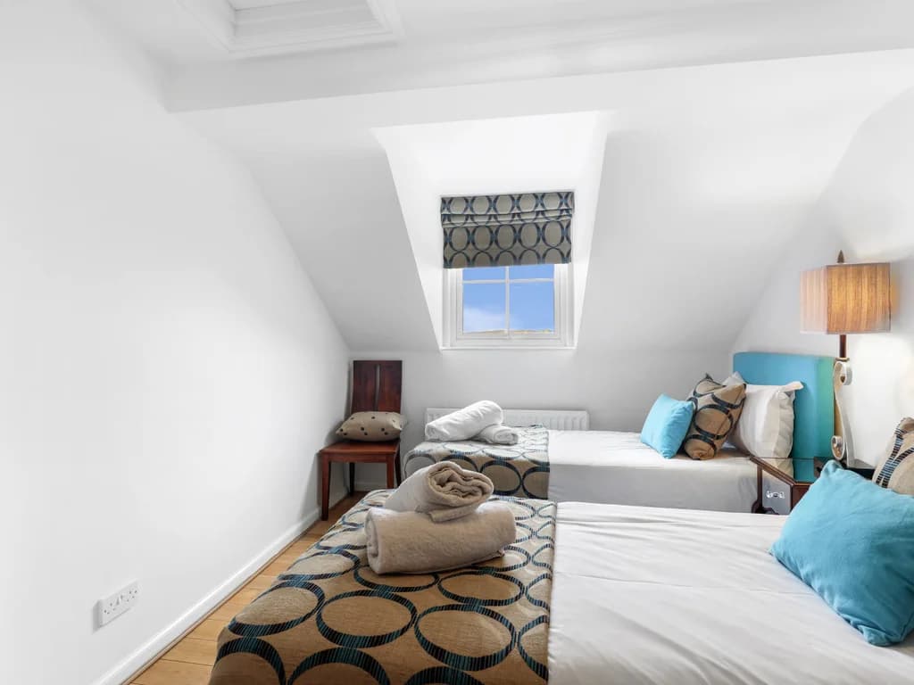 Twin bedroom with blue upholstered beds beneath sloped ceilings