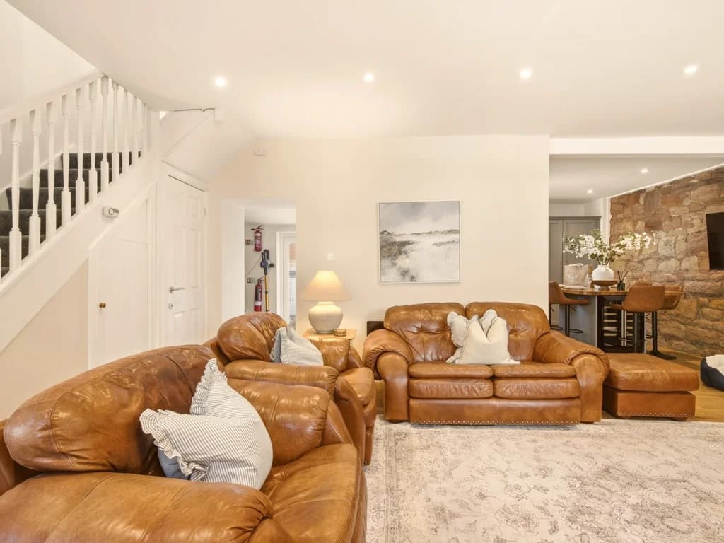 Open-plan living area with leather sofas and staircase to the first floor.