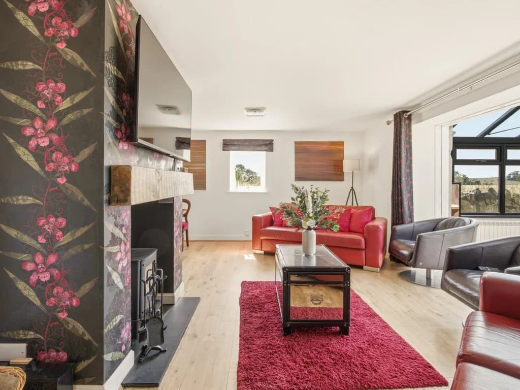 Bright lounge with red leather sofas, log burner and Smart TV
