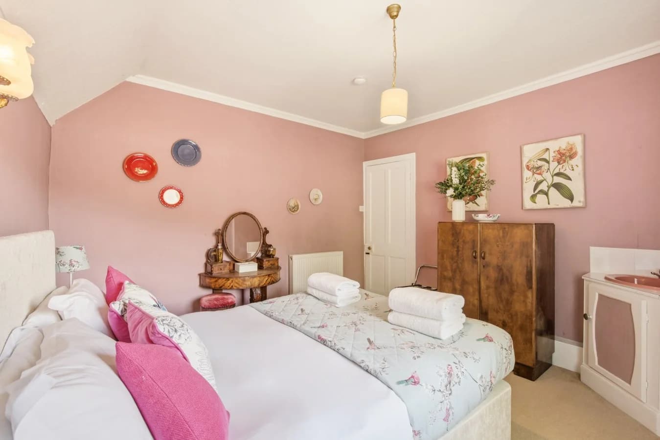 Double bedroom with floral bedding, vintage furniture and pink walls