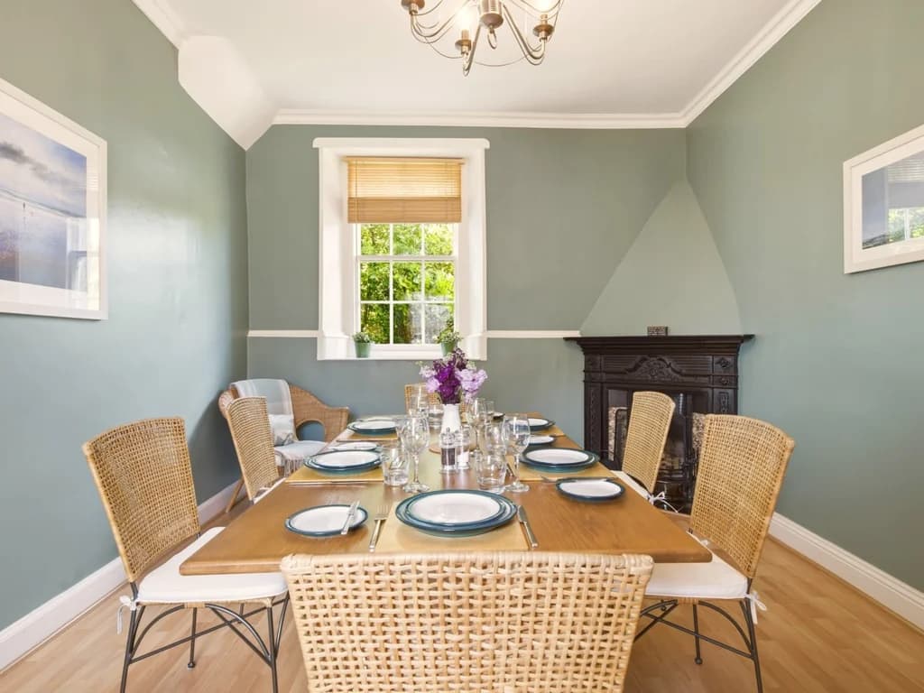 Spacious dining room with open fireplace and calming sage green walls