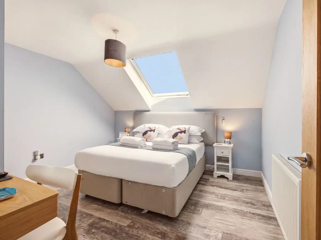Spacious king-size bedroom with skylight and soft neutral furnishings