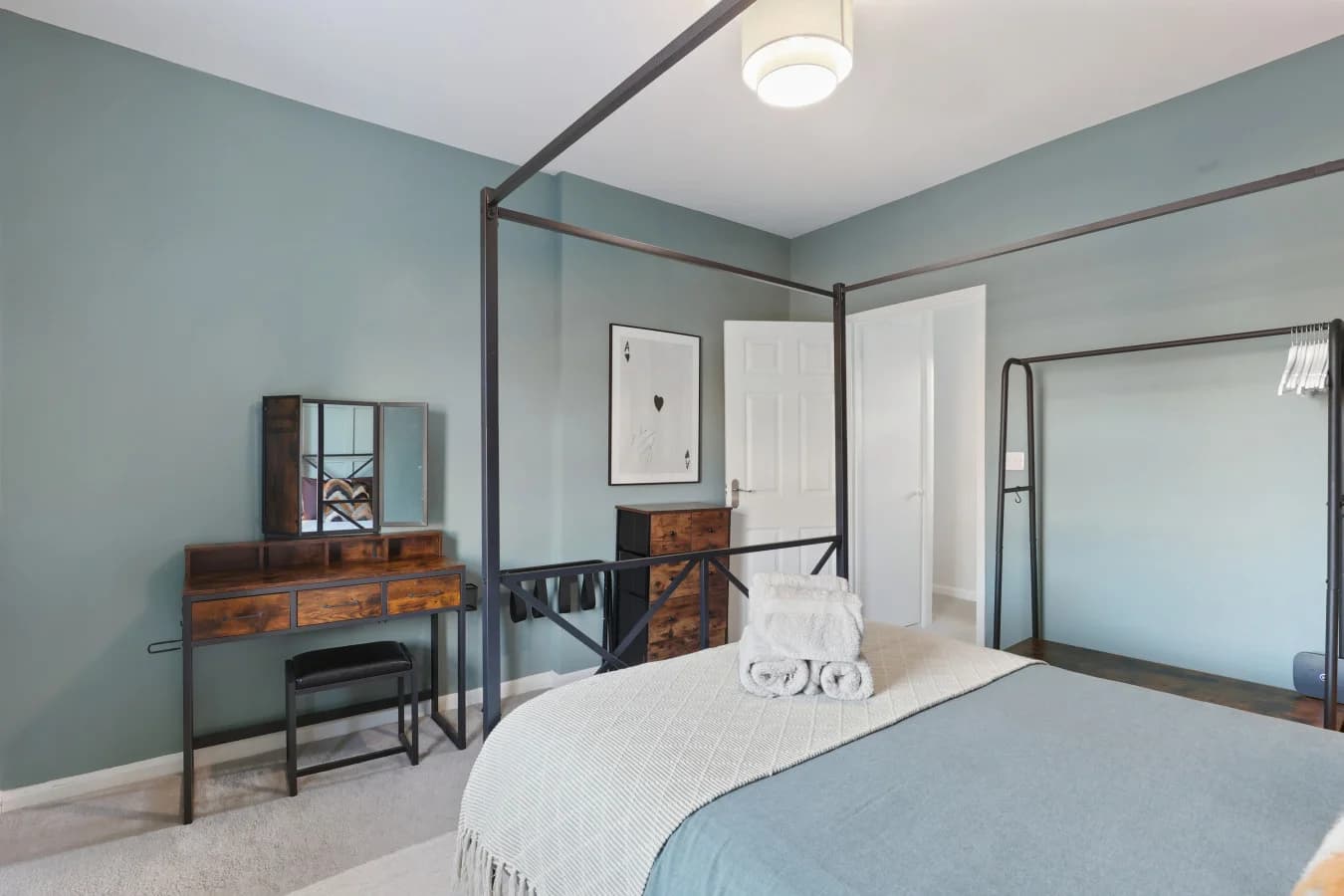 Four-poster bedroom with a vintage dressing desk and soft blue tones