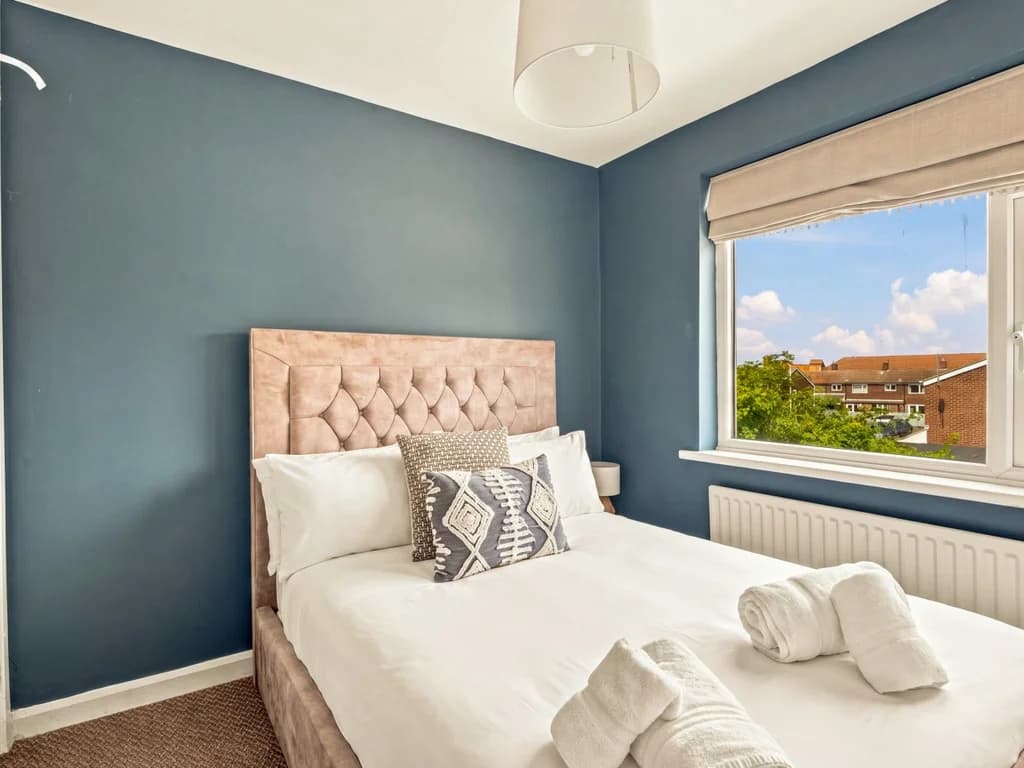 Small double bedroom with upholstered headboard and village rooftop views.