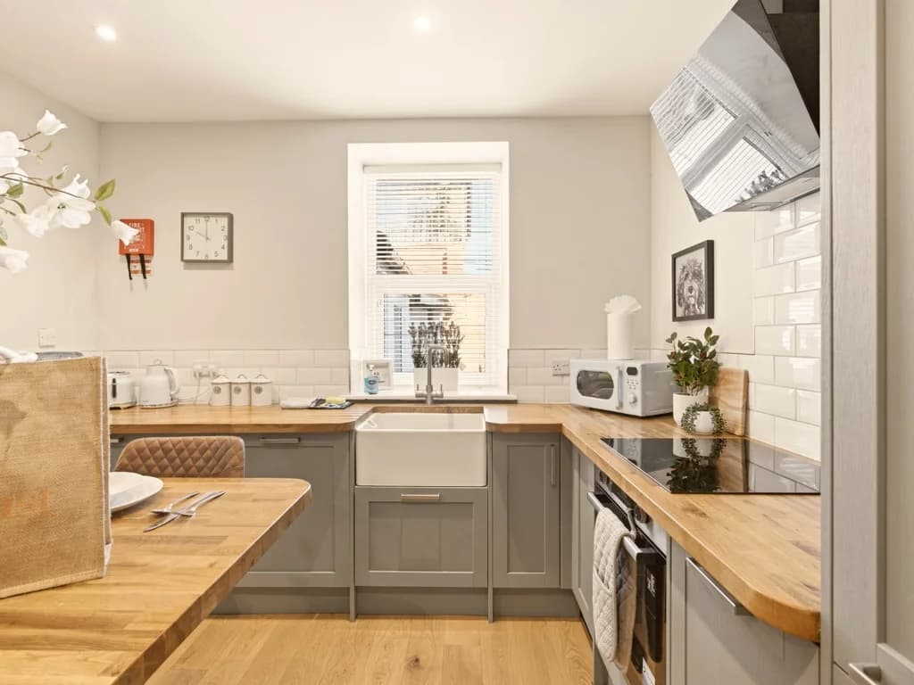 Well-equipped kitchen with shaker units, tiled splashback and dining island.