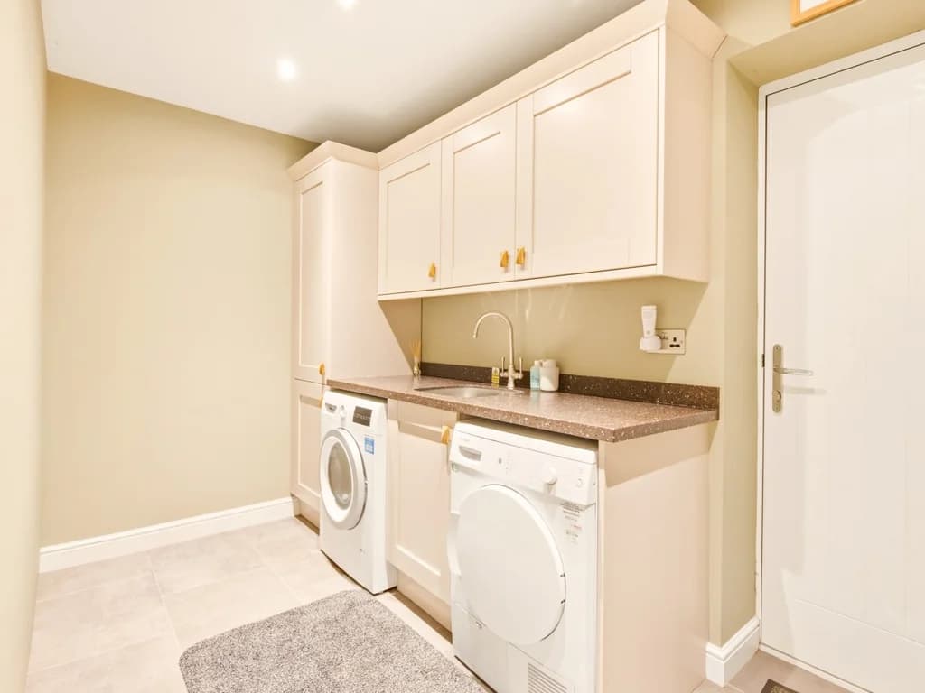 Utility room with washing machine, tumble dryer, sink and storage