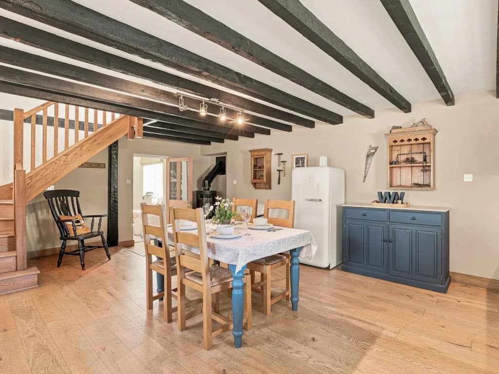 Spacious dining area with wooden staircase and exposed beams
