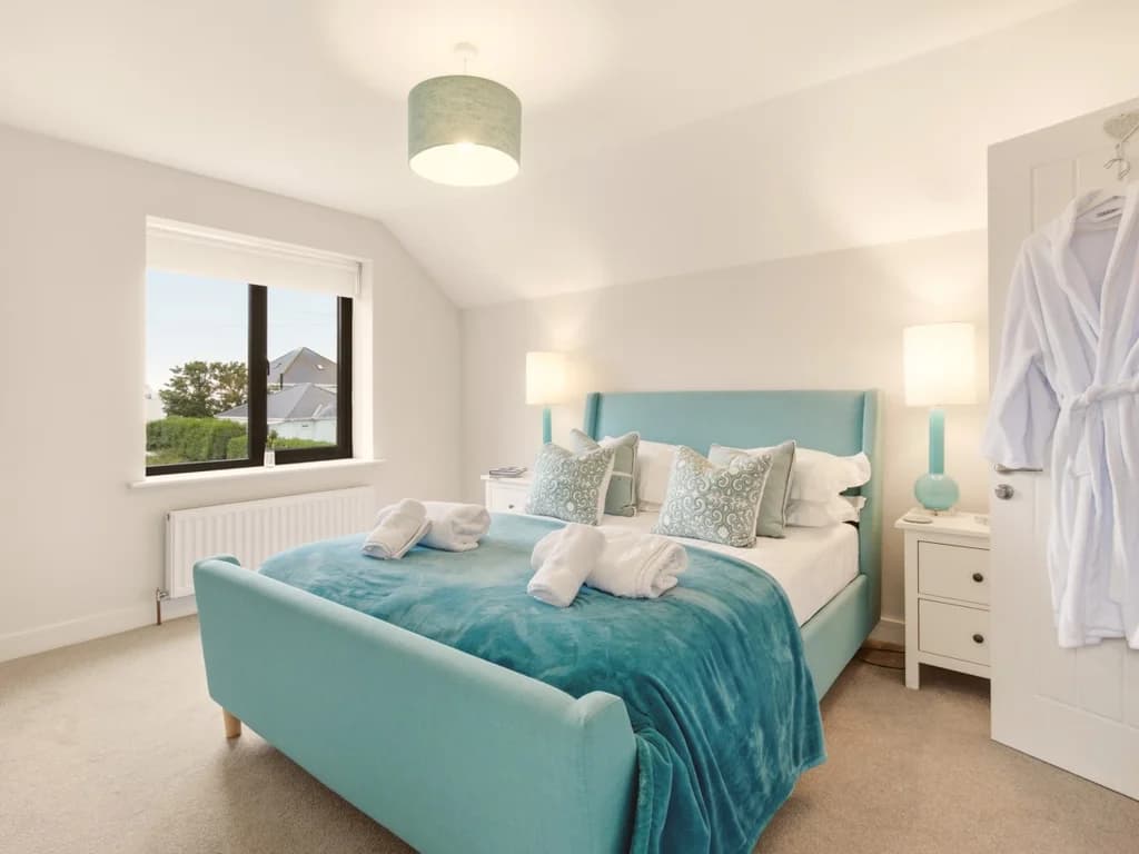 First floor king bedroom with teal upholstered bed and soft neutral décor