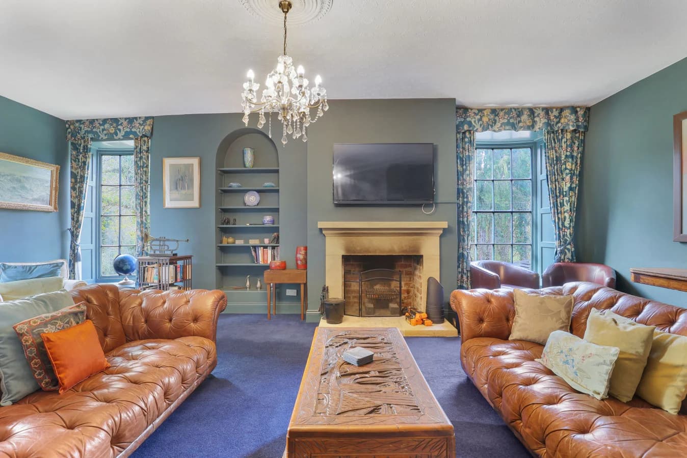 Spacious lounge with Chesterfield sofas, chandelier and feature fireplace