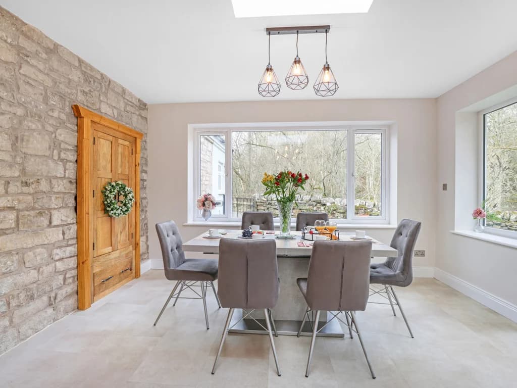 A sleek, modern dining set sits within a bright room featuring a rustic stone accent wall.