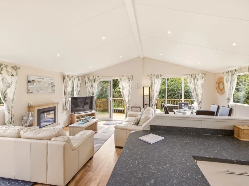 Open-plan lounge viewed from the kitchen with deck access and fireplace