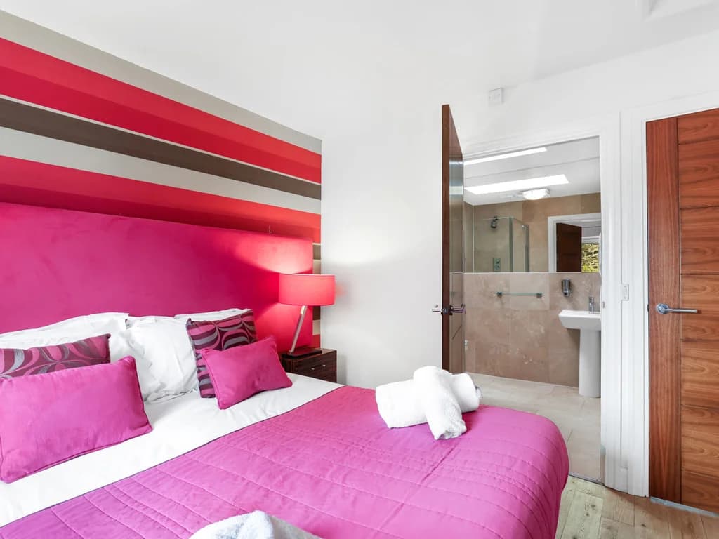 King bedroom with striped feature wall and contemporary furnishings