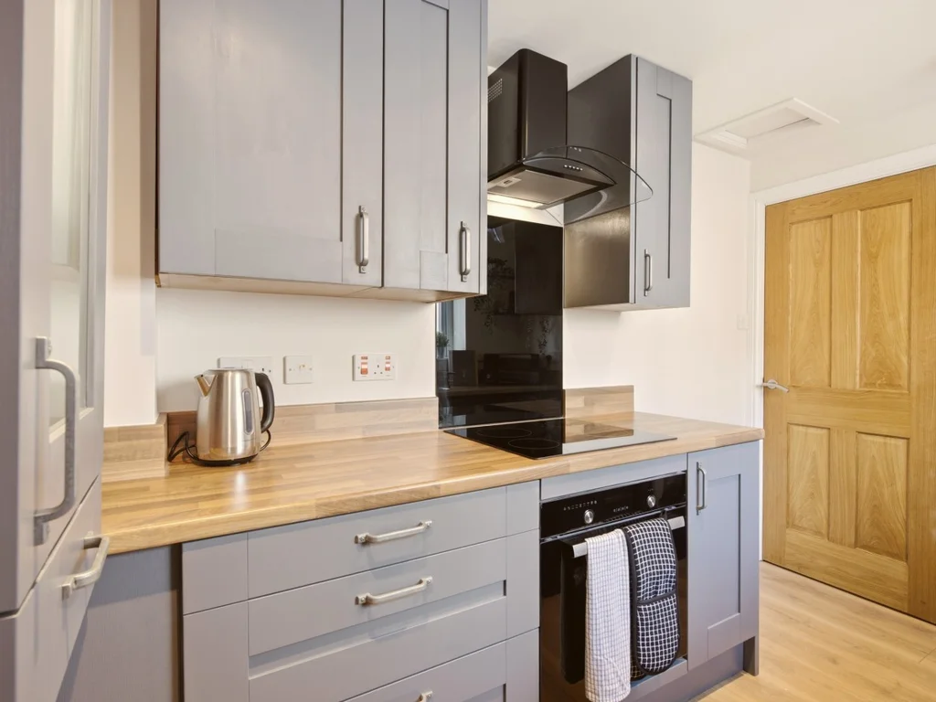 Modern kitchen with grey cabinetry and black glass splashback.