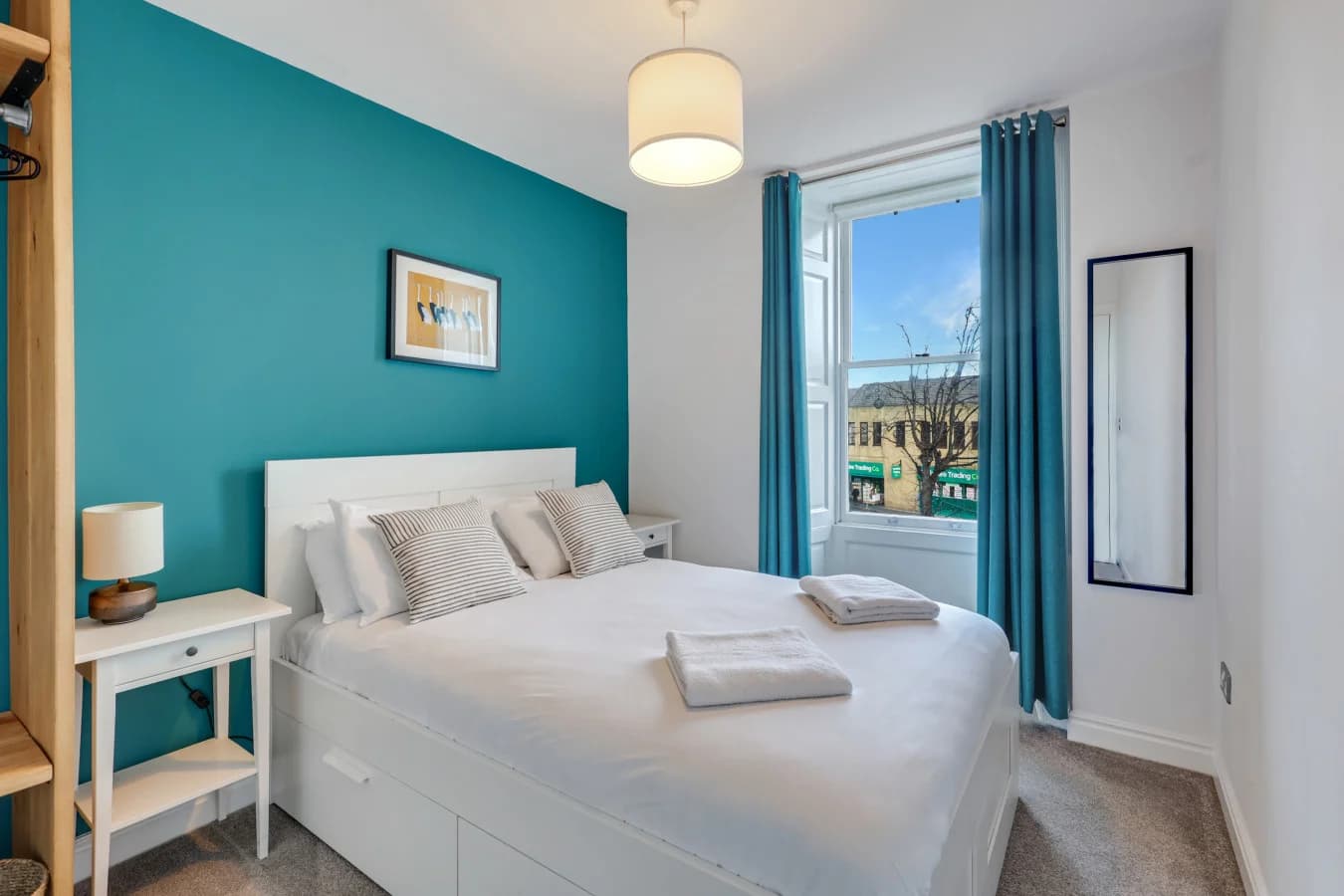 Double bedroom with teal feature wall and views across Alnwick rooftops