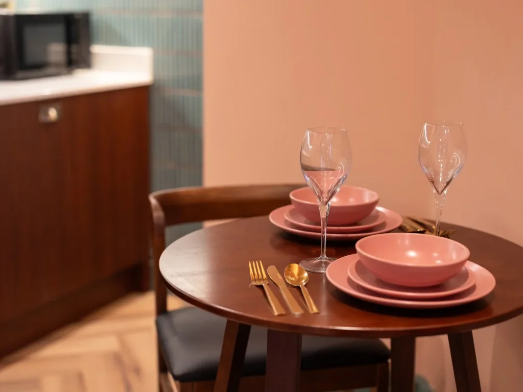 Dining table set for two beside the contemporary kitchenette.