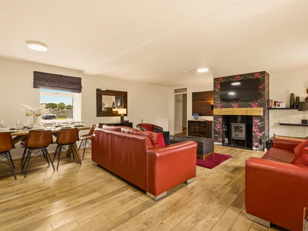 Bright open-plan living area with red sofas, dining space and kitchen.