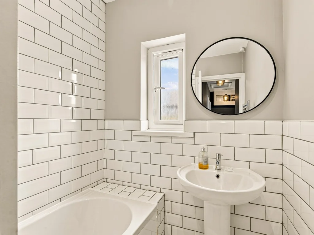Family bathroom with white subway tiles, bath and pedestal basin.