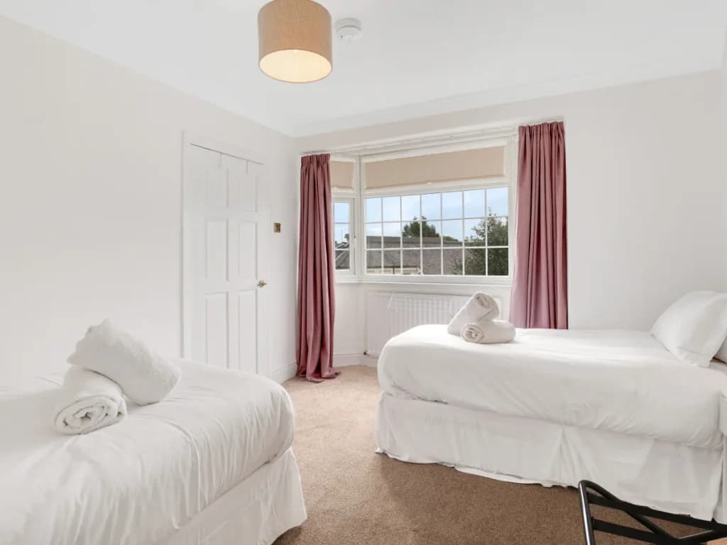 Twin bedroom with two single beds, large window and soft carpeting