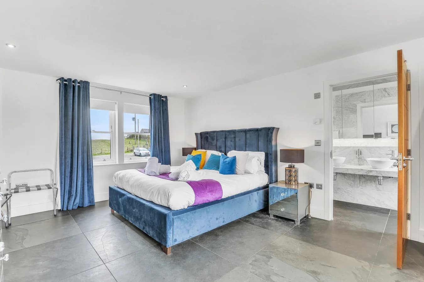 Super-king bedroom with blue upholstered headboard and ensuite
