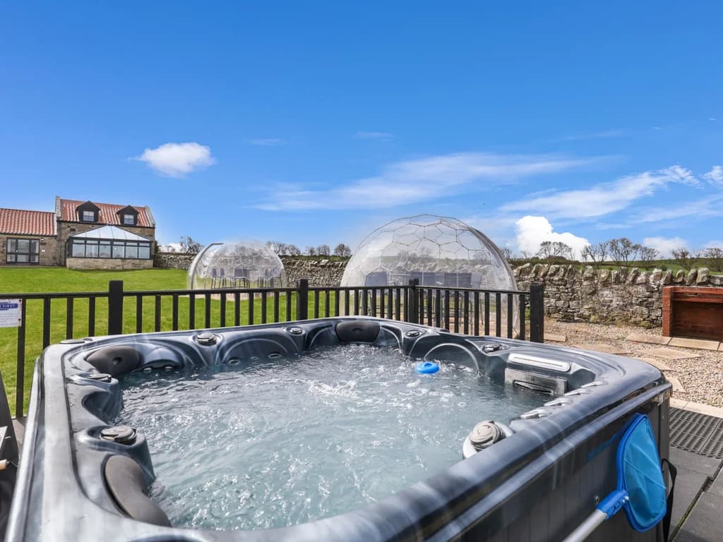 Shared hot tub overlooking the lawn with garden pods and paddock