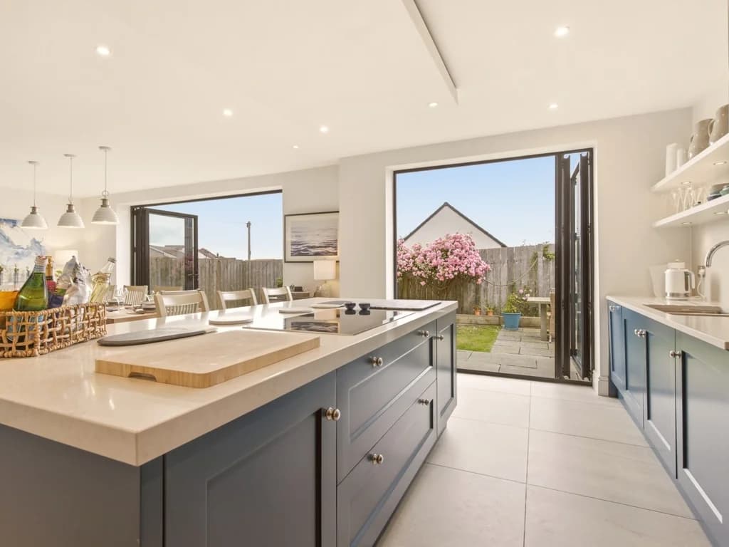 Contemporary kitchen with quartz island, blue cabinetry and garden access