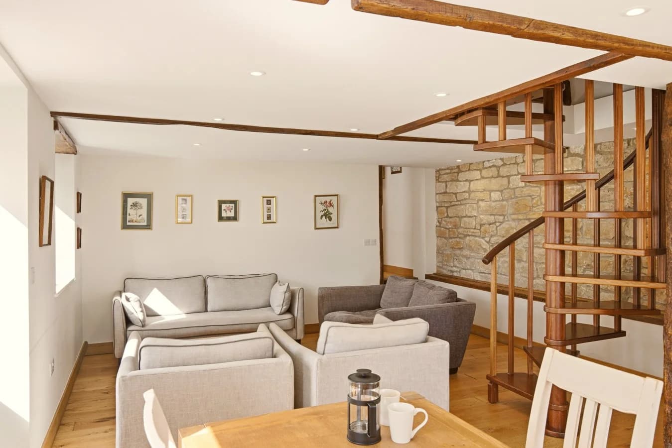 Lounge seating beneath exposed beams beside the spiral staircase