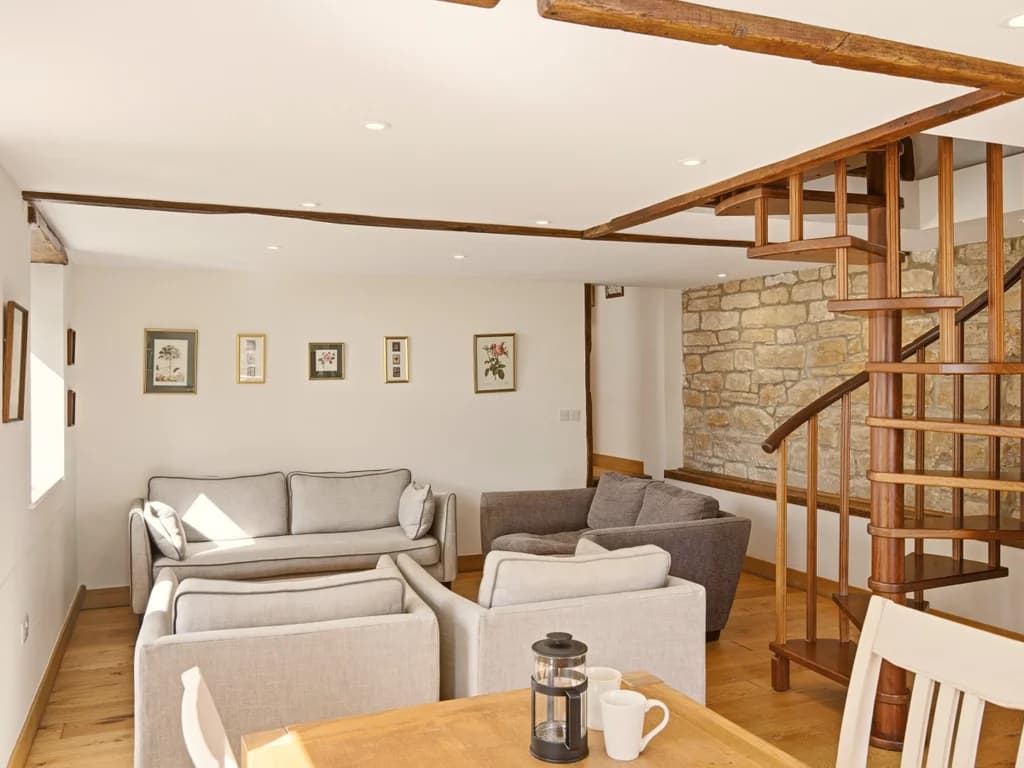 Lounge seating beneath exposed beams beside the spiral staircase