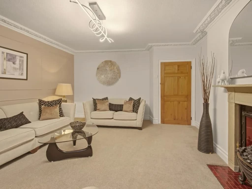Spacious living room with cream sofas, glass table and decorative details.