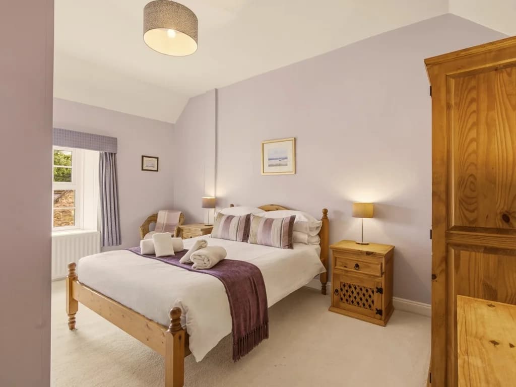 Comfortable double bedroom with oak wardrobe, bedside tables and armchair