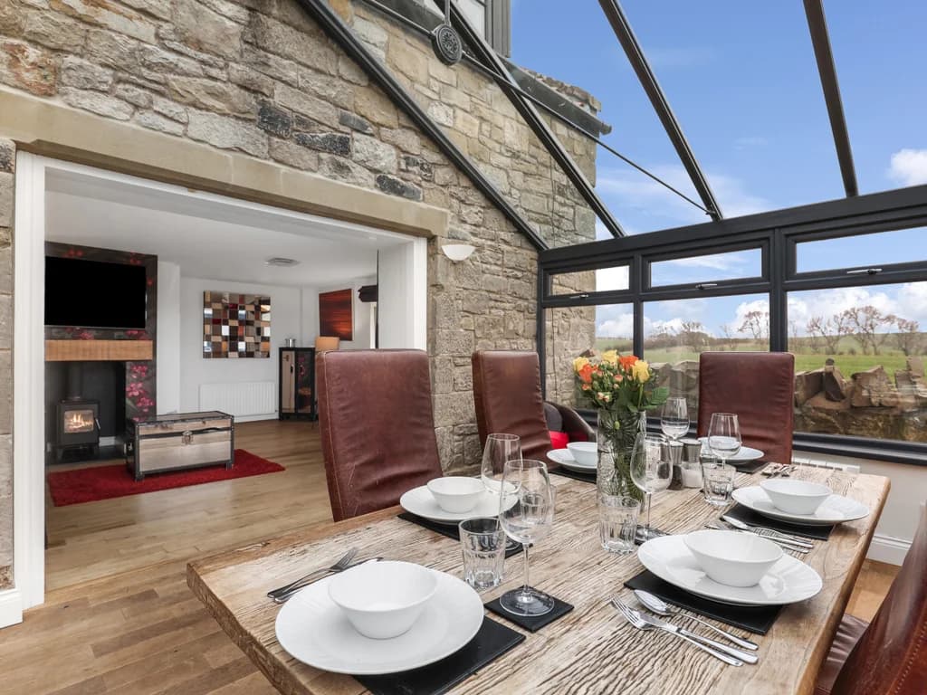 Conservatory dining area with stone walls and garden-facing windows