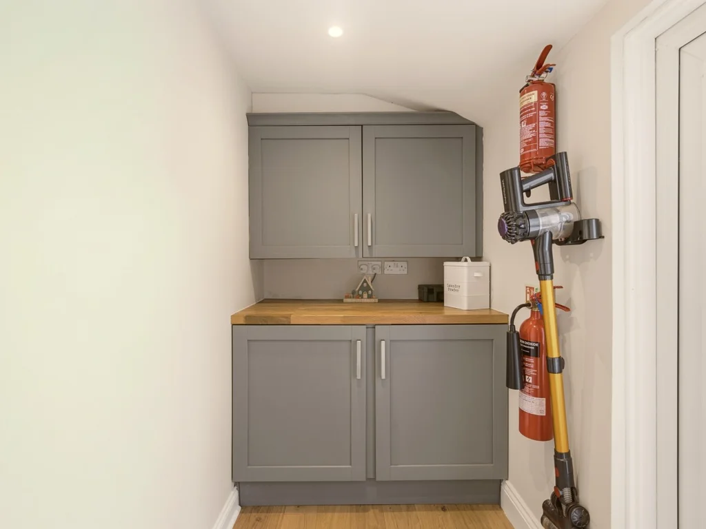Utility area with fitted storage cabinets and wooden worktop.