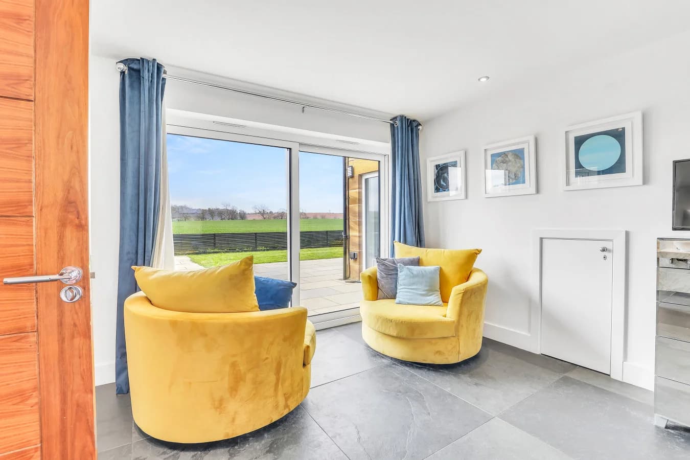 Yellow velvet chairs beside floor-to-ceiling countryside views