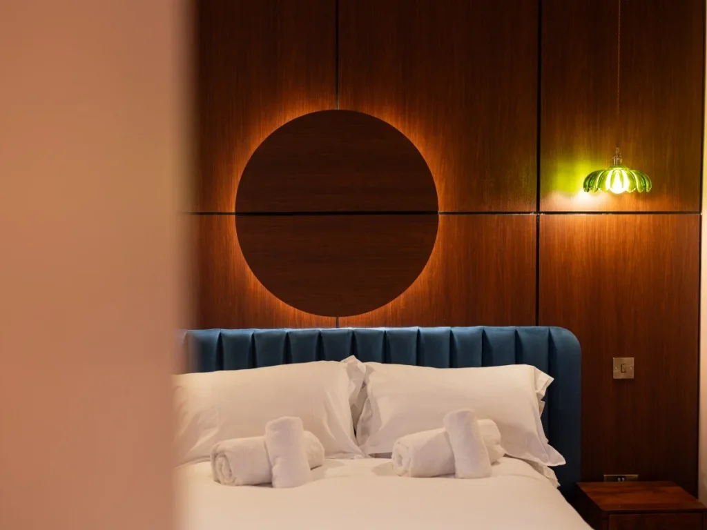 Double bed beneath a wood-panelled feature wall with bedside lighting