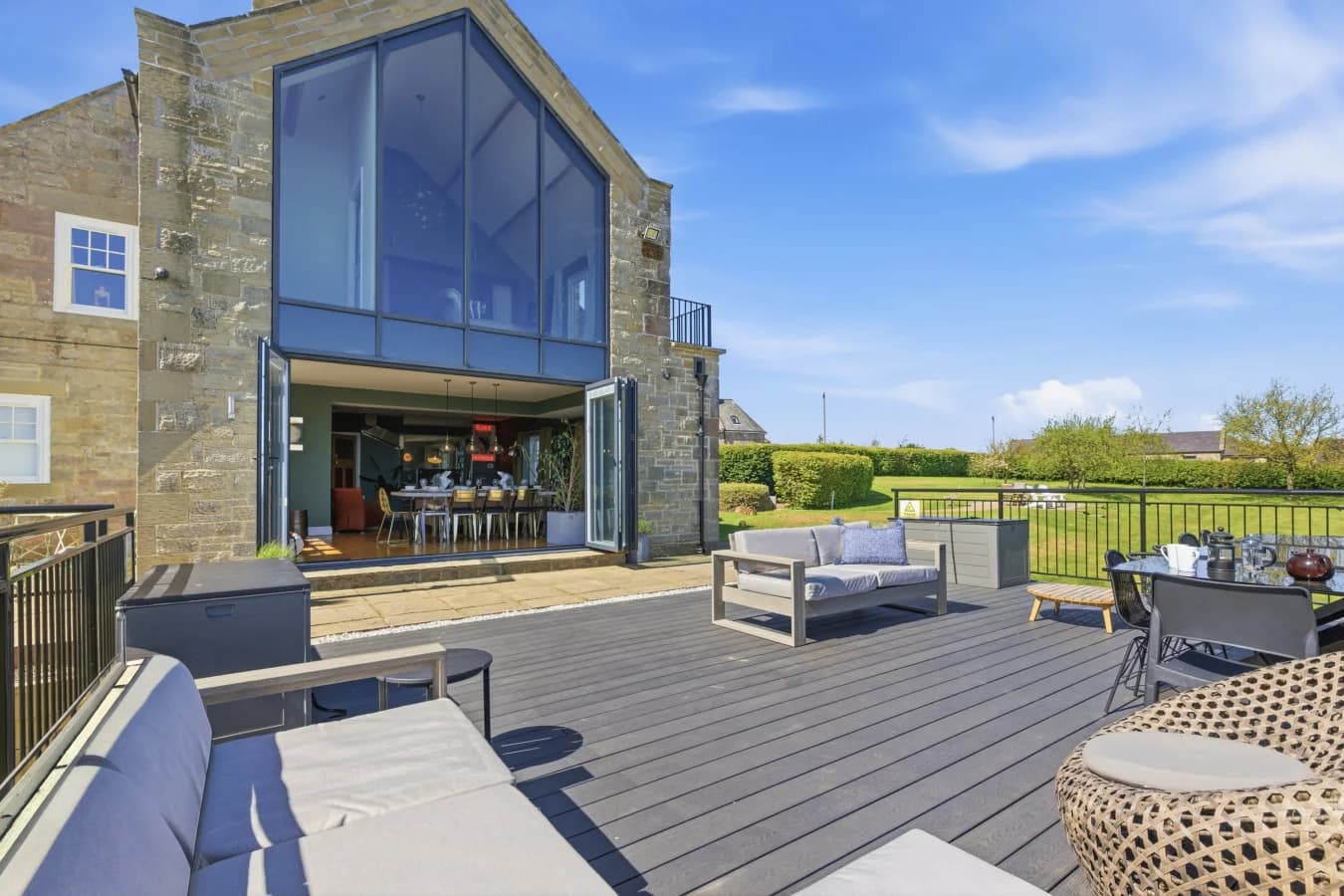 Statement glazed gable and composite deck with outdoor lounge furniture.