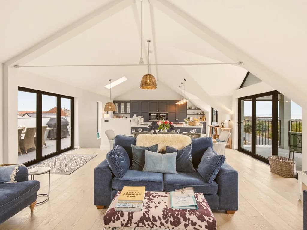 Bright open-plan lounge with vaulted ceiling and balcony access