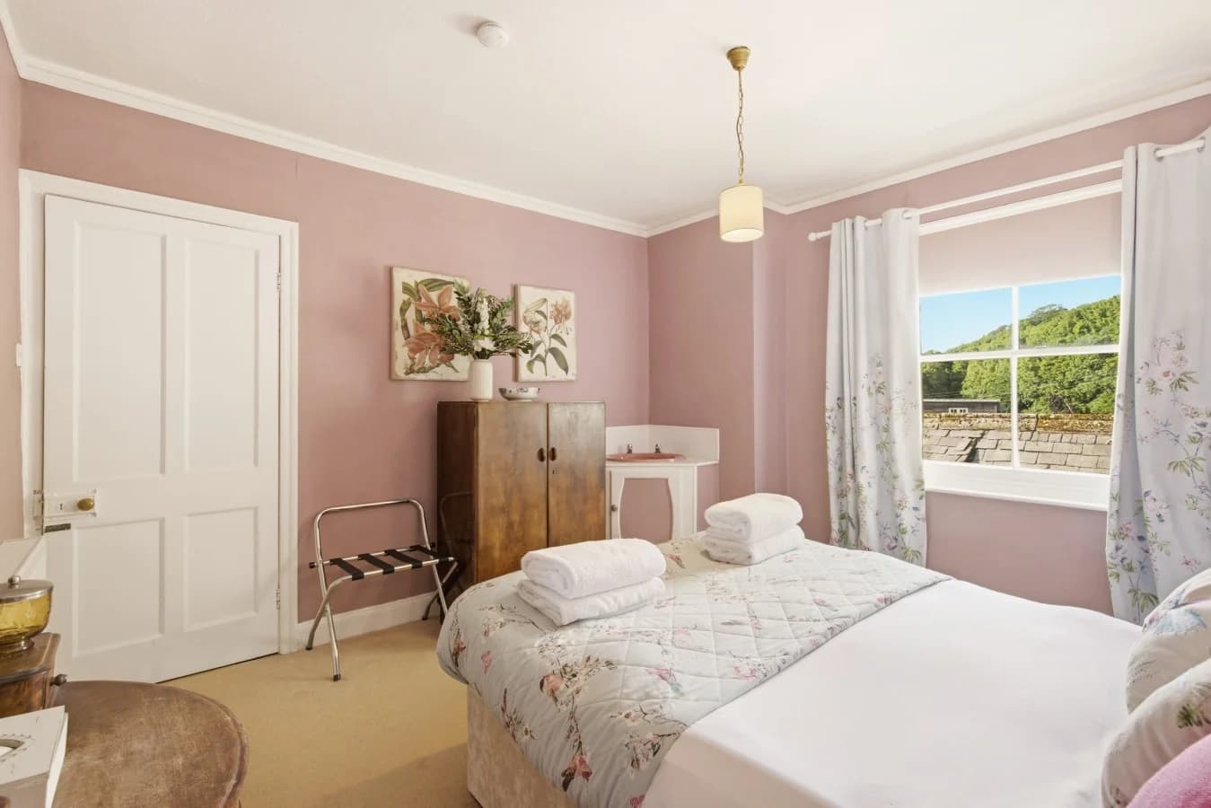 Bright double bedroom with floral décor and countryside-facing window