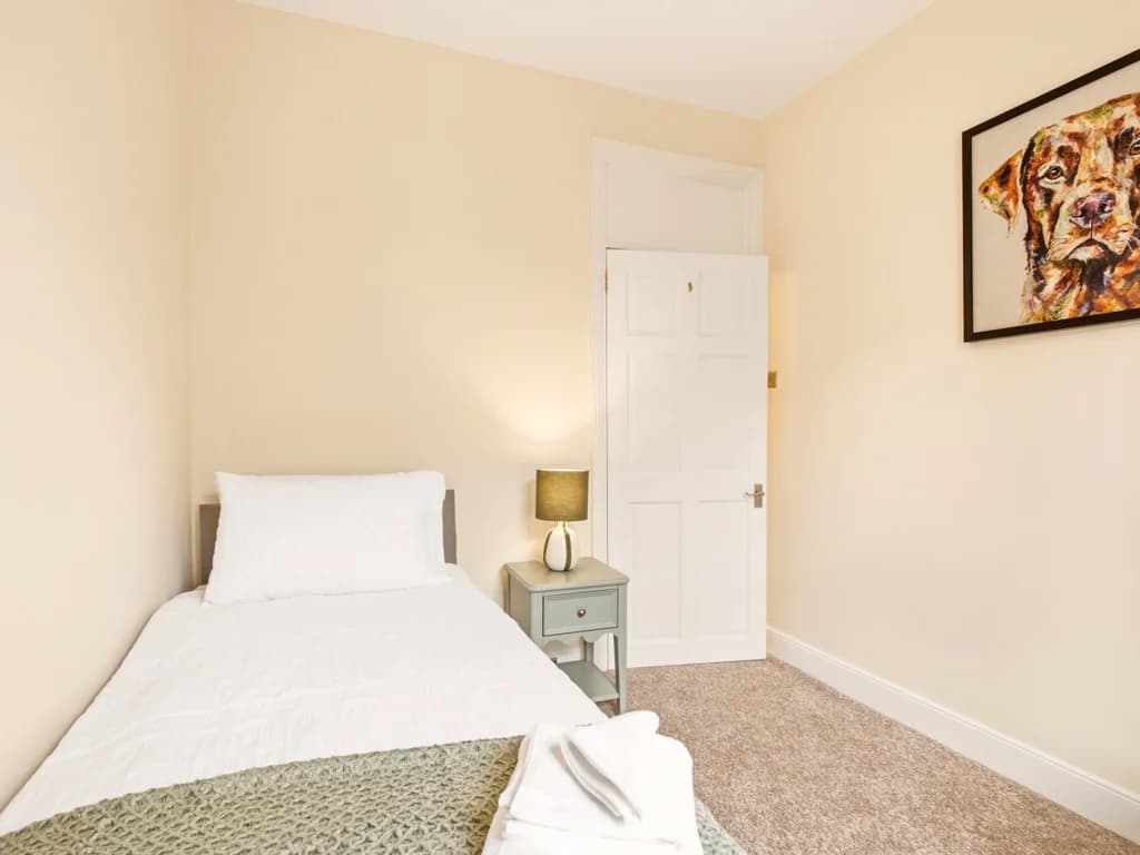 Second bedroom with single bed, futon chair and window.