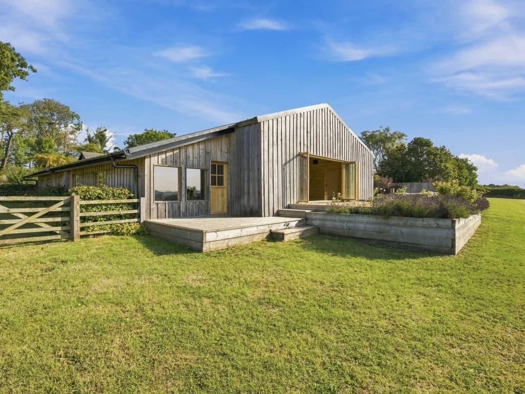 Rustic barn exterior with timber cladding and surrounding open lawns