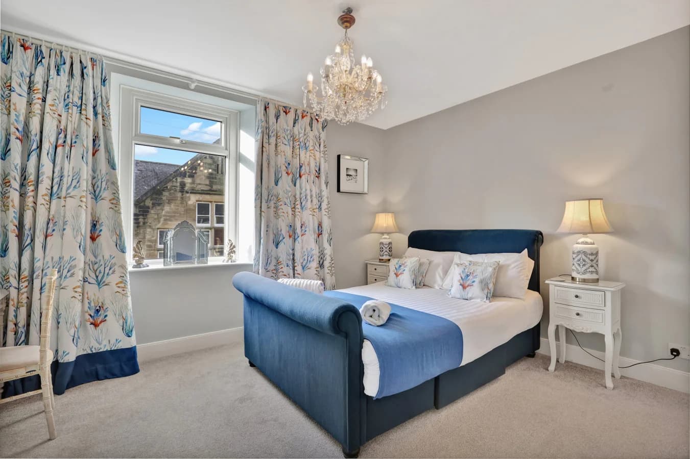 King bedroom with floral curtains, chandelier and street views