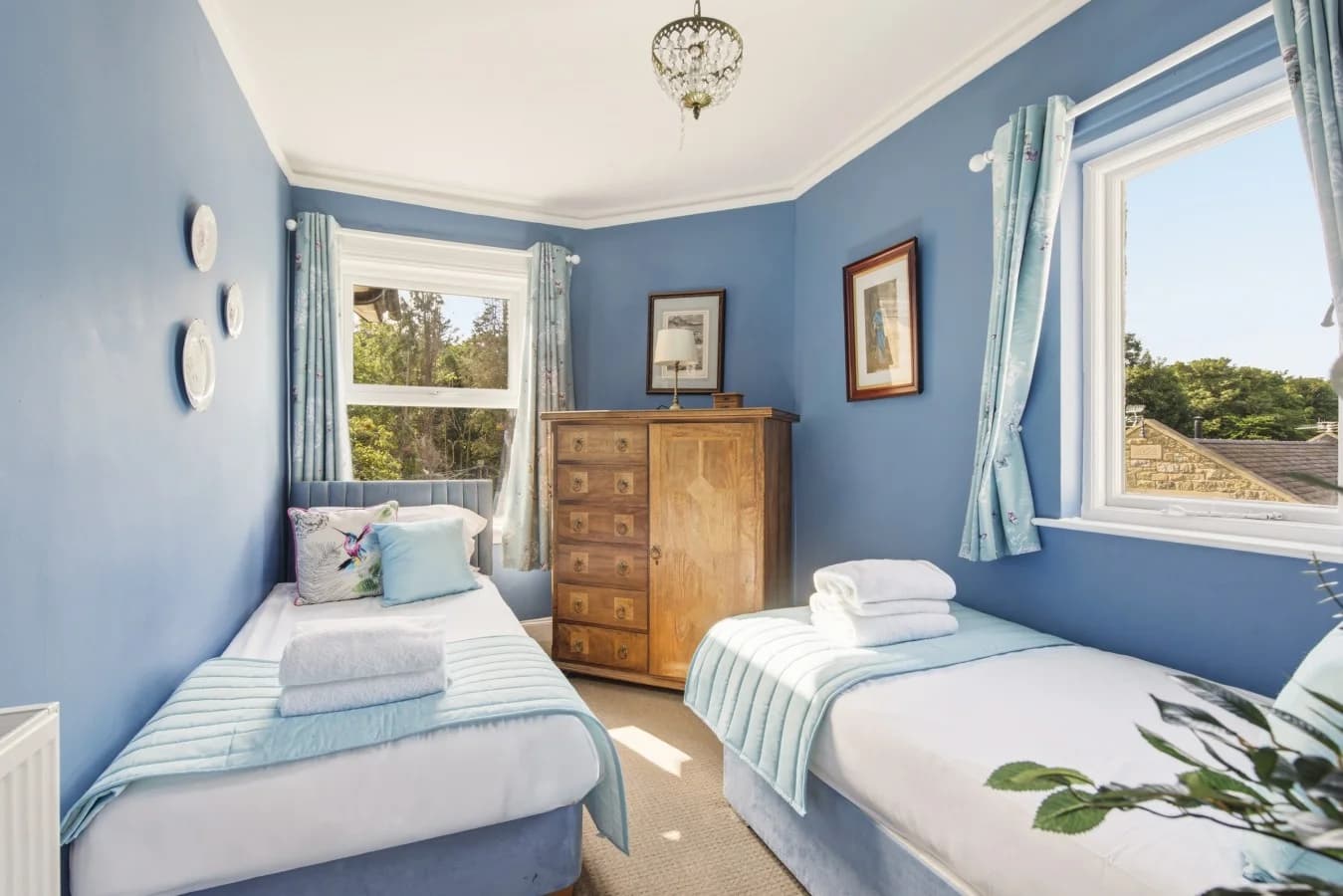Spacious twin room with blue décor, dresser and large window