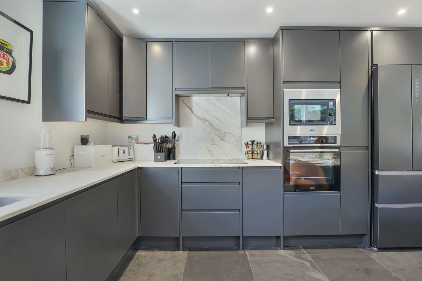 Contemporary kitchen with charcoal cabinetry and marble-effect splashback