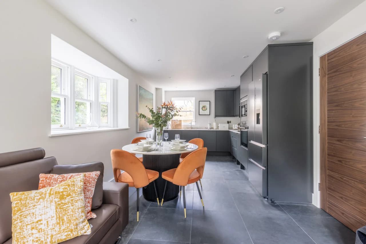 Open-plan living and dining area with quartz table and orange chairs