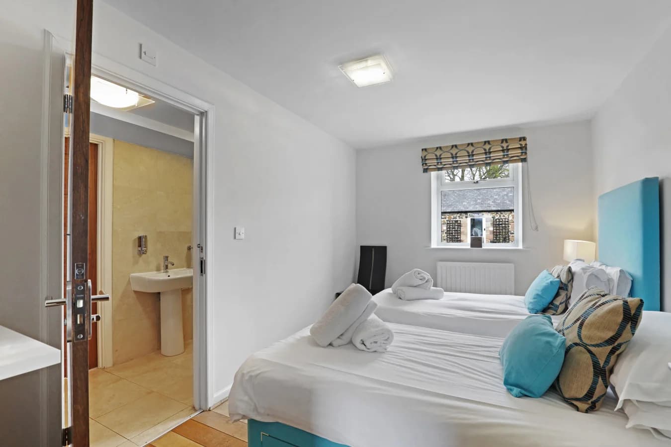 Twin bedroom with blue headboard and ensuite access