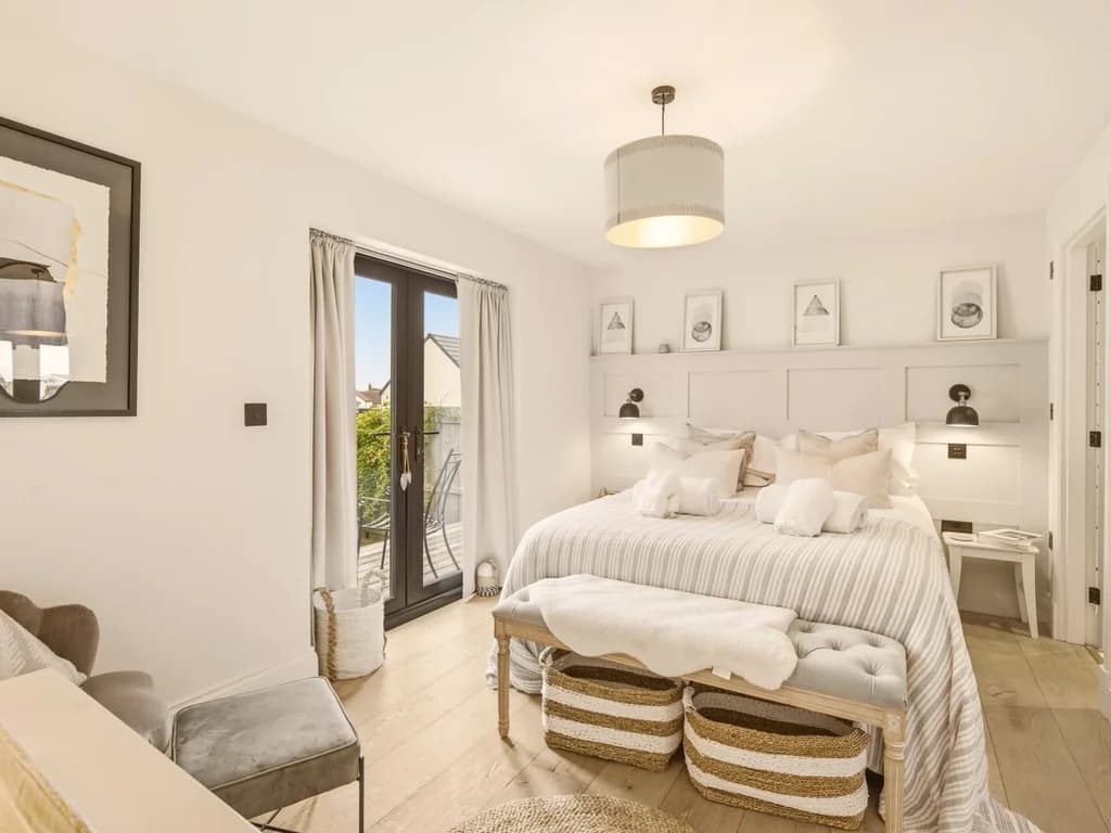 King bedroom with panelled headboard, bedside lighting and French doors