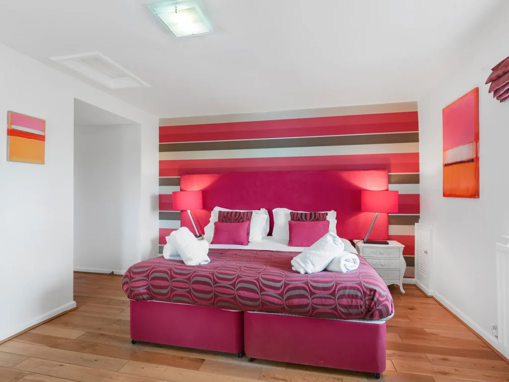 Super-king bedroom with pink headboard and dressing table