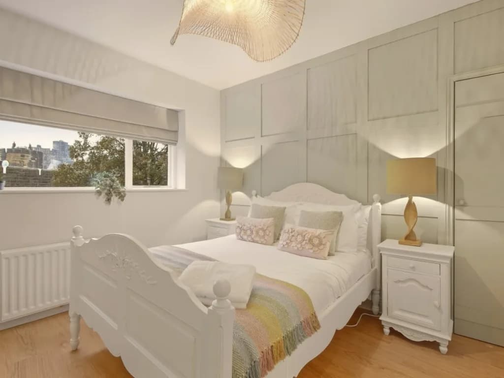 Bright double bedroom with panelled walls and natural light from the window.