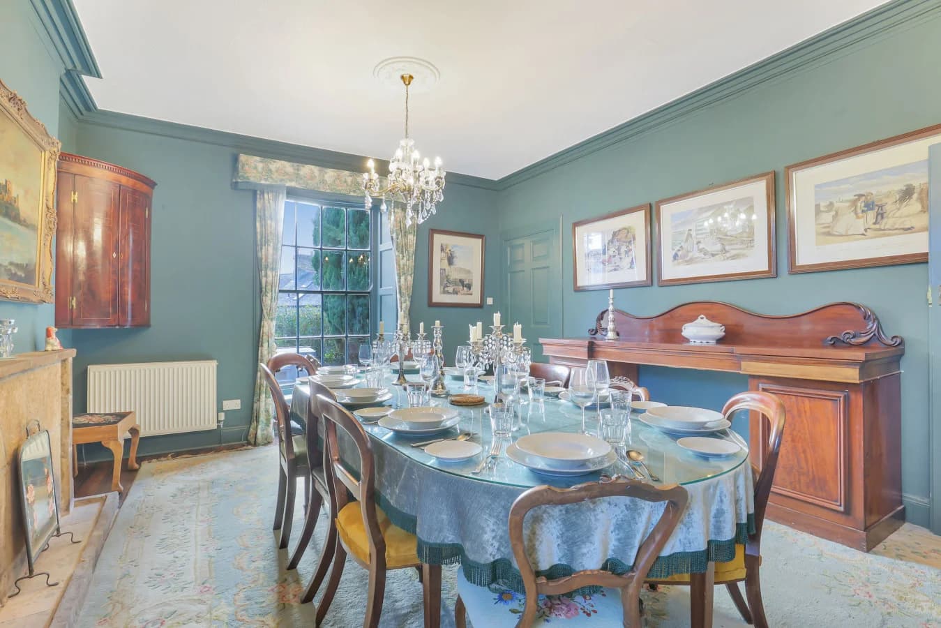 Formal dining room with teal walls, chandelier and seating for ten