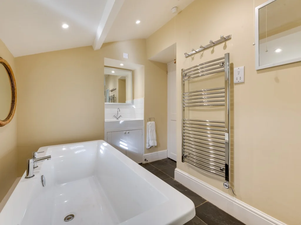 Bright family bathroom with bath, wash basin and heated towel rail.