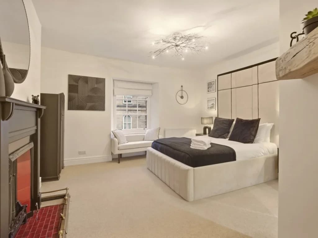 Wider double bedroom view with window seat and decorative fireplace.